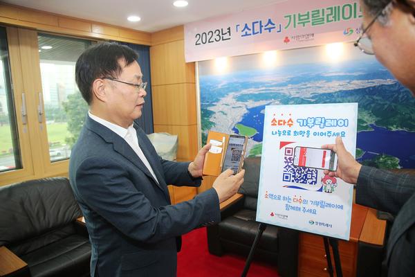 홍남표 창원특례시장이 ‘소다수 기부 릴레이’에 참여하기 위해 QR코드를 찍고 있다